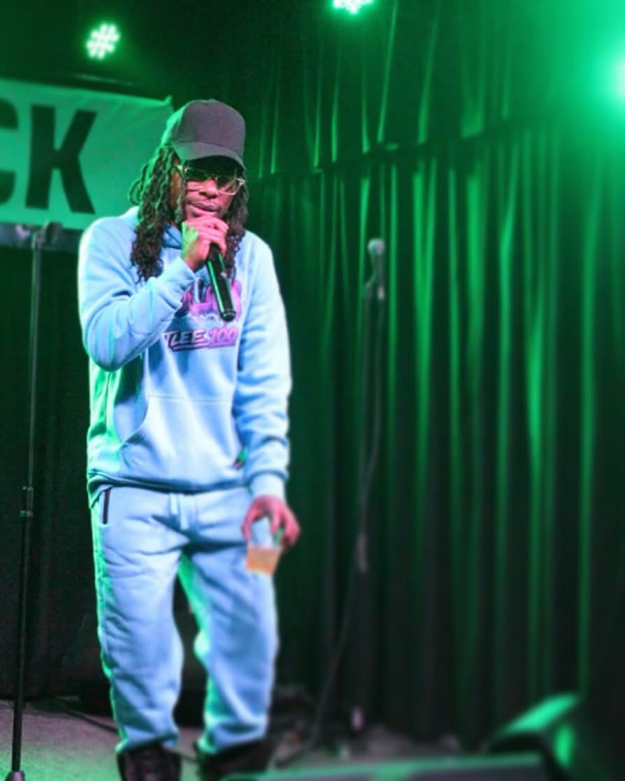 T Lee 100 performing live under green stage lights